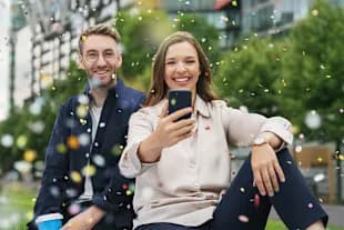 Man and woman with smartphone in confetti rain